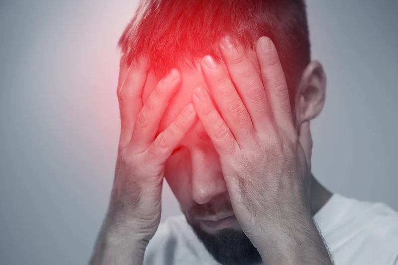 גבר מכסה את פניו בידיו בזמן כאב ראש